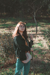Portrait of young woman standing on field in forest