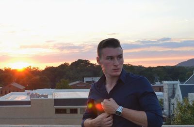 Portrait of young man in city during sunset