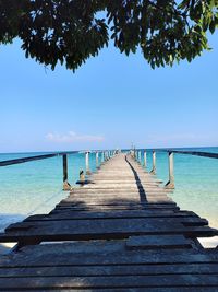 Wooden pier over sea against blue sky