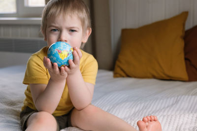 Child boy hugging the earth globe, save the earth. 3 years old kid holding a toy model. baby toddler