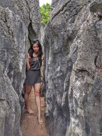 Full length of young woman standing amidst rock formations