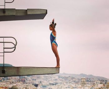 Low angle view of woman jumping against sky