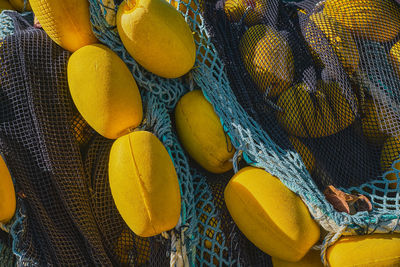 Pile of multi-colored fishing nets with yellow floats dry on the pier, close-up, 