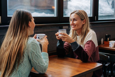 Two pretty young women are talking in a bar over coffee.