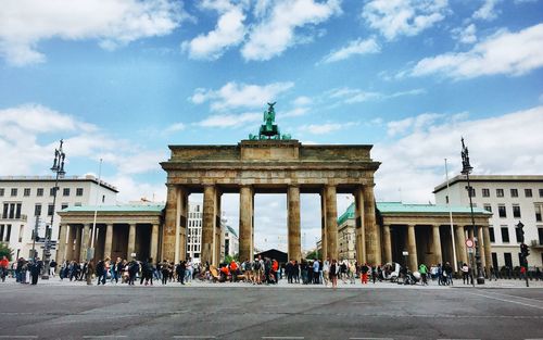 Tourists in front of brandenburg gate against sky