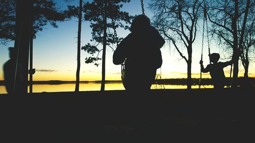 Rear view of silhouette man standing by tree against sky