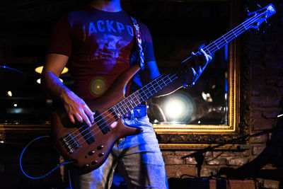 Midsection of man playing guitar at nightclub