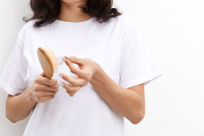 Midsection of woman holding dentures against white background