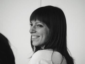 Side view of smiling young woman looking away while standing against wall