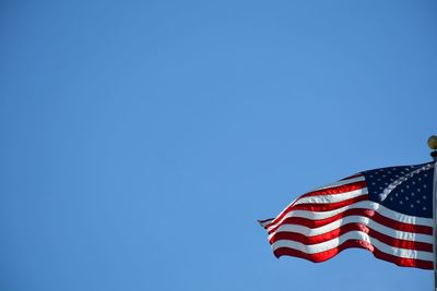 Low angle view of flag against clear blue sky