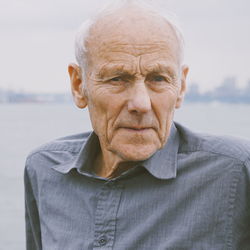 Close-up portrait of senior man against river