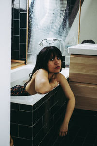 Young woman sitting in bathroom