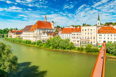 Buildings by lake against sky