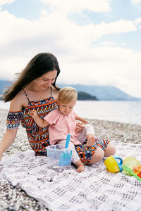 Mother and girl on beach against sky