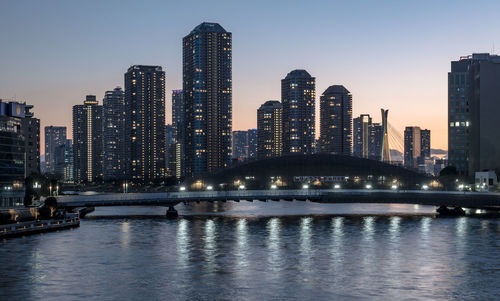 Buildings by river against sky in city