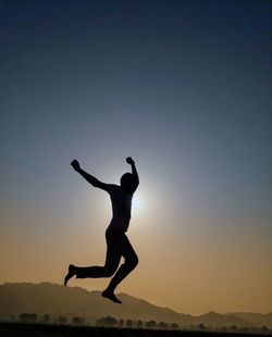 Full length of woman jumping against sky during sunset