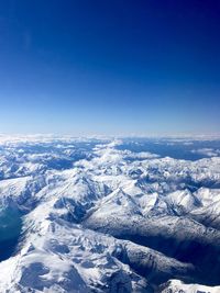 Aerial view of snowcapped mountains against clear blue sky