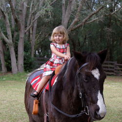 Portrait of girl riding horse on field