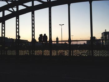 Silhouette people standing on bridge against sky during sunset