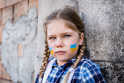 Portrait of girl with face paint against wall
