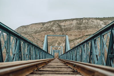 Footbridge over railroad track against sky