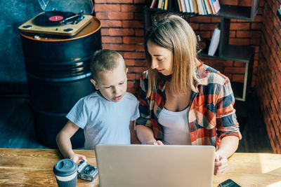 Family bonding, mom and son use laptop for learning.
