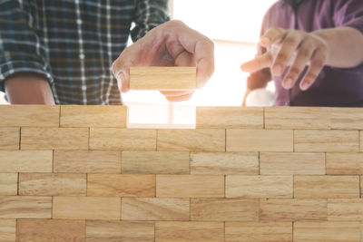 Midsection of people building toy block