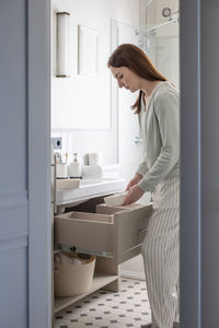 Side view of woman standing by drawer