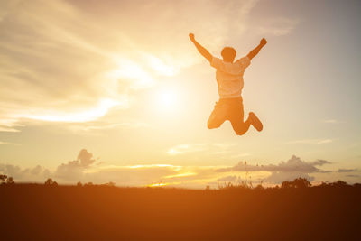 Low angle view of silhouette man jumping against sky during sunset