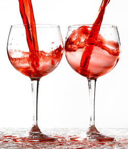 Close-up of wineglass on glass against white background