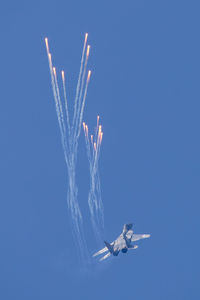 Low angle view of airshow against clear blue sky