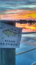 Close-up of text on shore against sky during sunset