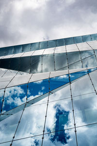 Glass building with reflection against cloudy sky