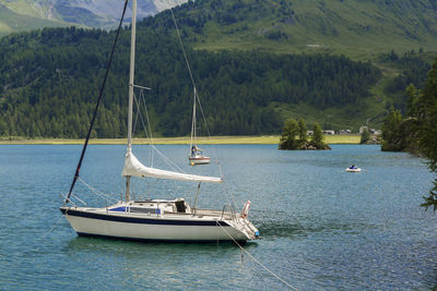 Boats sailing on lake against mountains