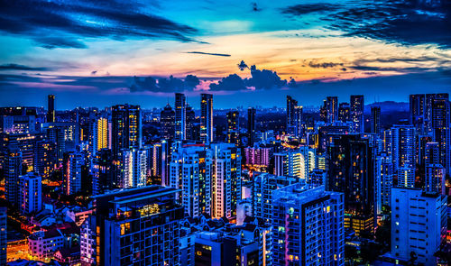 Aerial view of illuminated buildings in city against sky during sunset