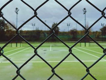 Full frame shot of chainlink fence with tennis court in the background 