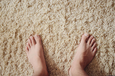 Low section of man standing on beige rug