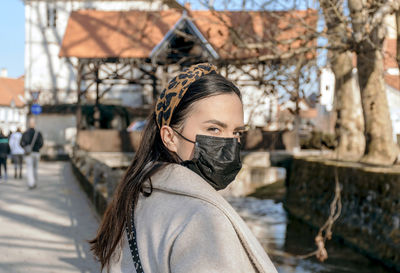 Beautiful young woman wearing black face mask, looking at camera. epidemic, covid, corona virus.