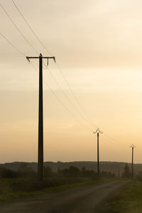 Electricity pylon on field against sky during sunset