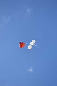 Low angle view of balloons flying against blue sky