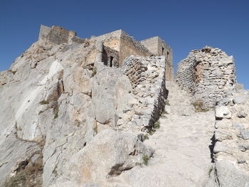 Low angle view of rocks on mountain against clear sky