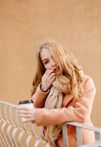 Beautiful young woman with takeaway coffee outdoors in cold weather
