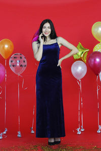 Full length of a young woman holding red balloons