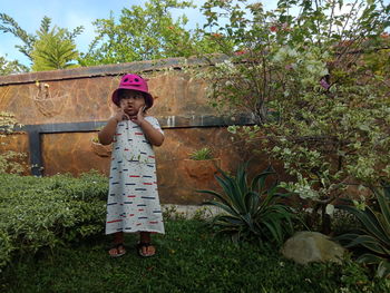 Full length of cute girl standing against plants