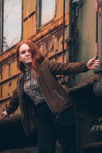 Portrait of young woman standing against train