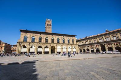 Group of people in front of historical building against clear blue sky