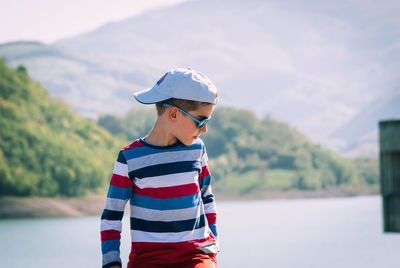 Cute boy standing against lake