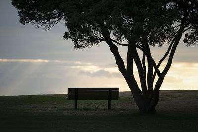 Empty bench on field against sky during sunset