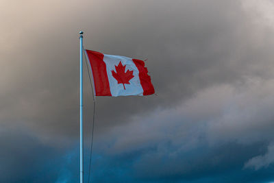 Low angle view of canadian flag on pole against sky