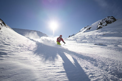 Man skiing on snowcapped mountain against sky